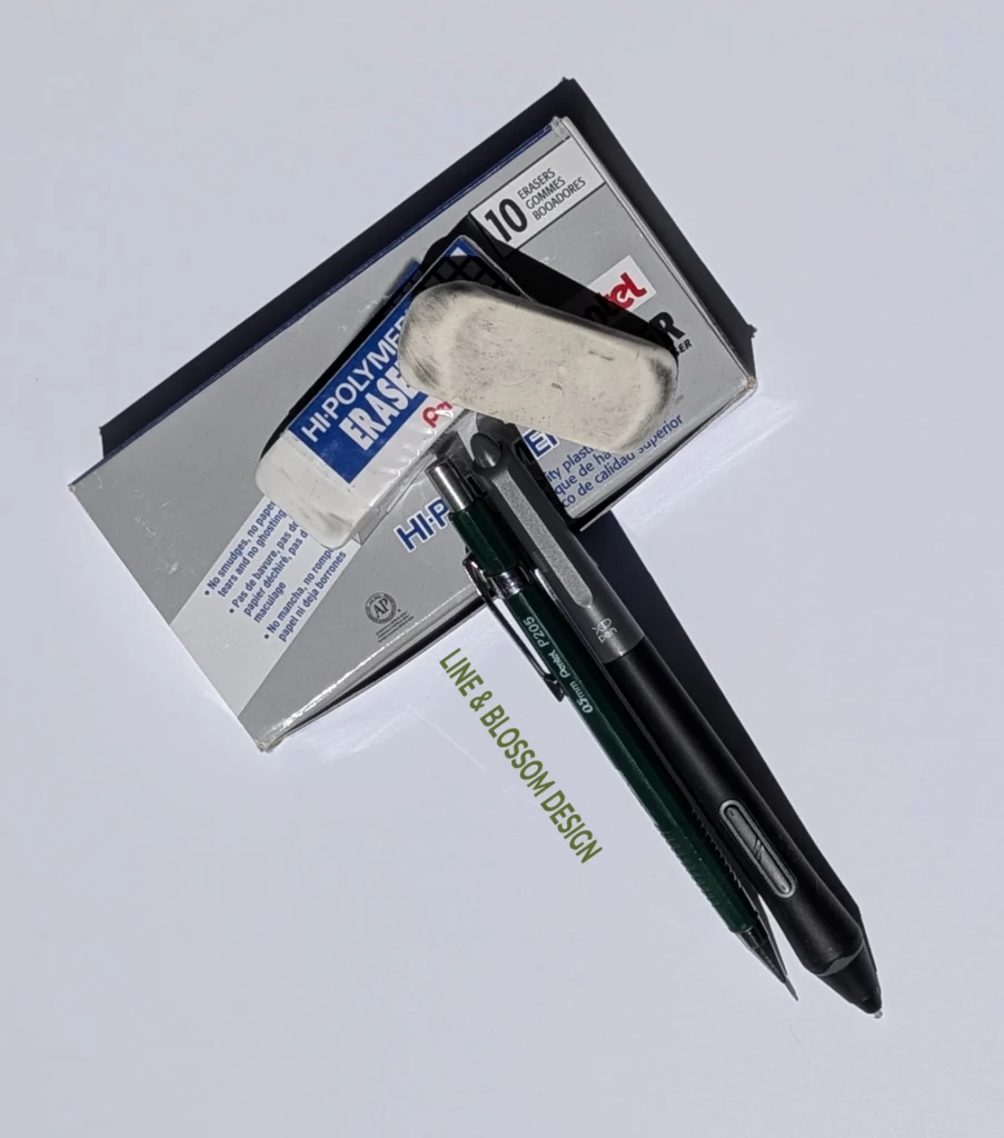My box of Pentel erasers with two used one sitting on top along with my favorite Pentel P205 mechanical pencil and the stylus for my drawing tablet.