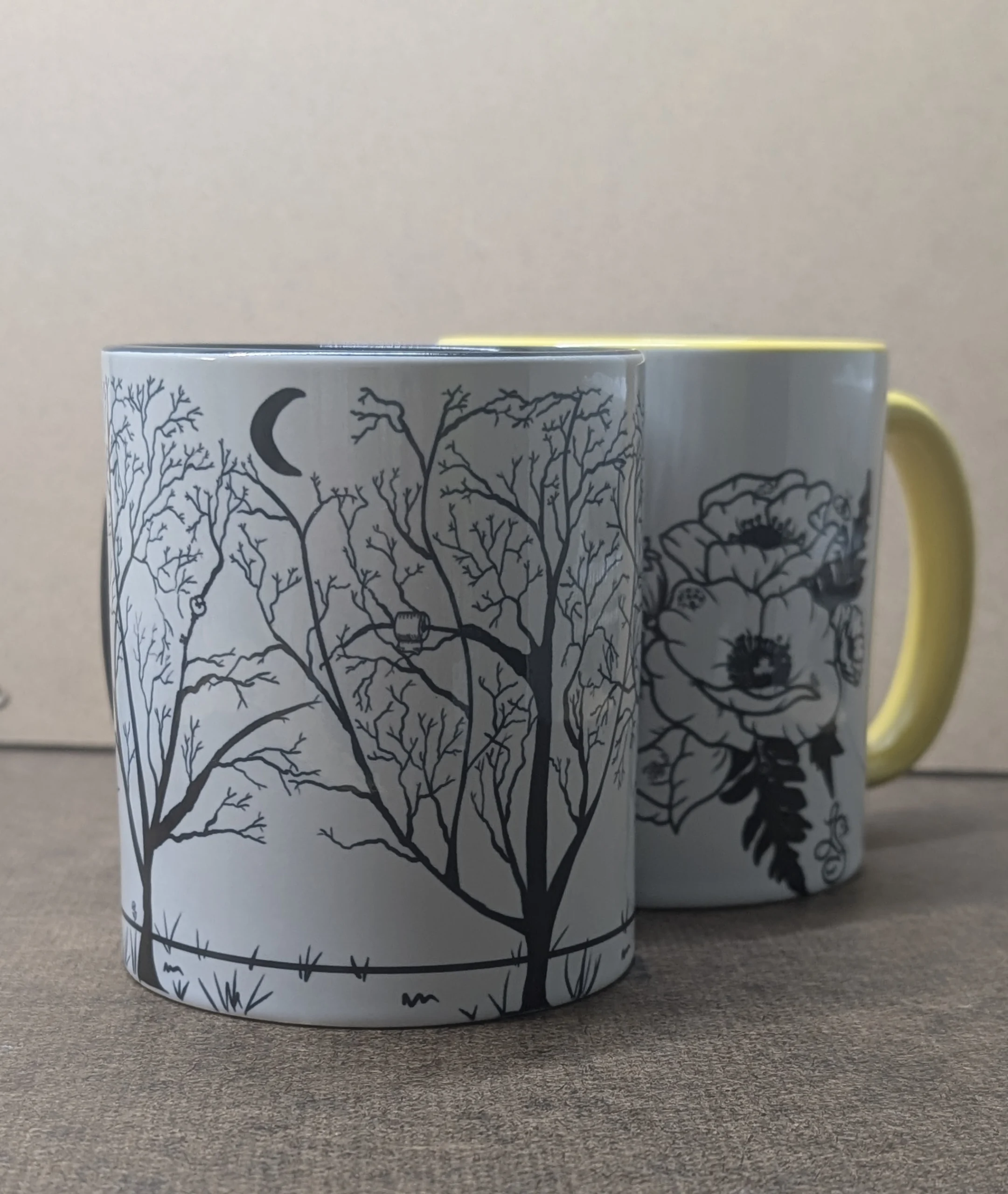 black and white art. Winter Trees mug with the Poppy Mug in the background
